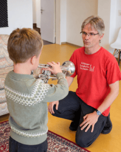 Helmut Pöhner gibt einem Jungen Tipps, wie er der Trompete erst Töne entlocken kann.
